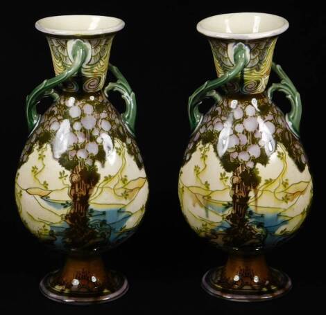 A pair of late 19thC Minton's Secessionist pottery vases, in the manner of Louis Solon, of shouldered circular form, with entwined bark handles, on oval feet, each decorated with scenery, predominately in green and purple, faint impressed marks beneath, e