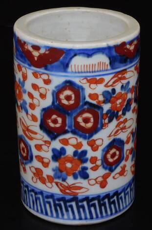 A Meiji period Japanese cylindrical Imari brush pot, profusely decorated with flowerheads between banding, in orange and blue, 16cm H.