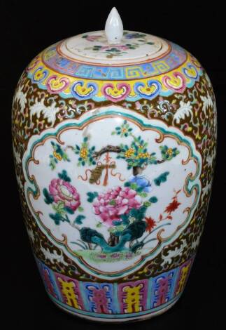 A Chinese porcelain ovoid vase and cover, decorated in a famille rose palette with panels of flower sprays, and further flowers on a brown ground, all within brightly coloured ryui and lappet borders, 34cm H.