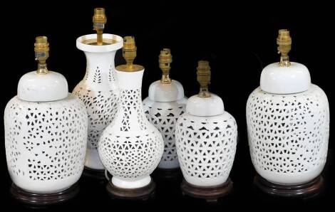 A Chinese pierced white porcelain table lamp, of bulbous form with pierced body on a wooden plinth base with lamp fitting, 39cm H, and various other similar vases. (6)