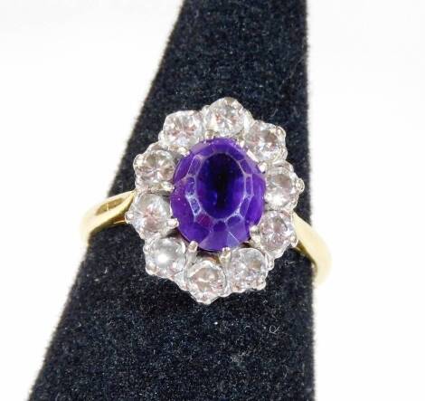 An amethyst and diamond cluster ring, with central oval cut amethyst surrounded by ten round brilliant cut diamonds, each in claw setting, on a yellow metal band, marked 18ct gold, ring size Q, 5.4g all in.