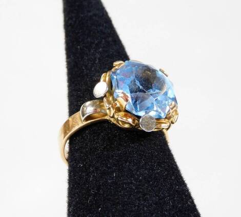 An 18ct gold cluster ring, with central pale blue stone in four claw setting, with white and yellow metal surround, on a yellow metal band, marked 750, ring size M, 4.9g all in.