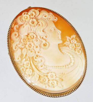 A 9ct gold framed shell cameo brooch, with oval cameo of maiden looking left, with flowing hair with flowers, the plain frame with reeded border, 4.3cm x 5.6cm, 14.6g all in.