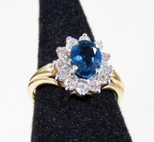 A 9ct gold cluster ring, with central blue topaz surrounded by white stones, in claw setting, ring size L, 2.9g all in.