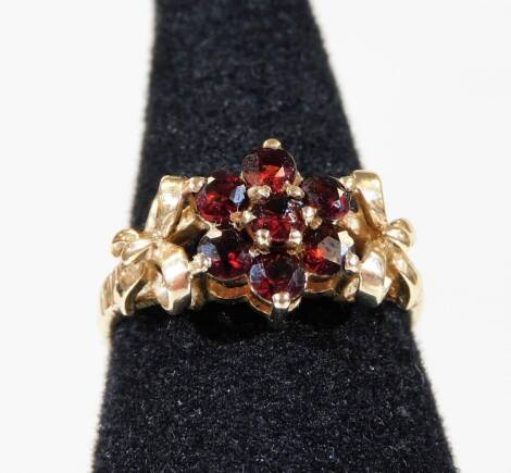 A 9ct gold garnet bow ring, with central garnet flower, with bow to either side, ring size P½, 3g all in.