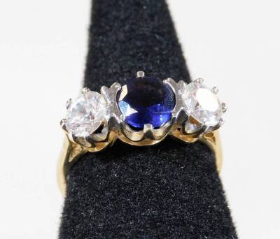 A 9ct gold three stone dress ring, with central bluey/purple stone flanked by two white stones, each in claw setting, ring size L, 2.7g all in.