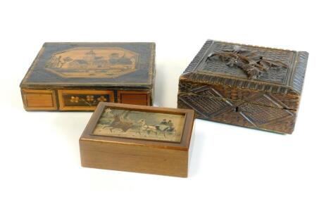 An early 20thC Prisoner of War straw work box and cover, set with building and trees, 5cm H, 21cm W, 19cm D, a heavily carved box with hinged lid and a further oak casket set with horse and carriage scene. (3)