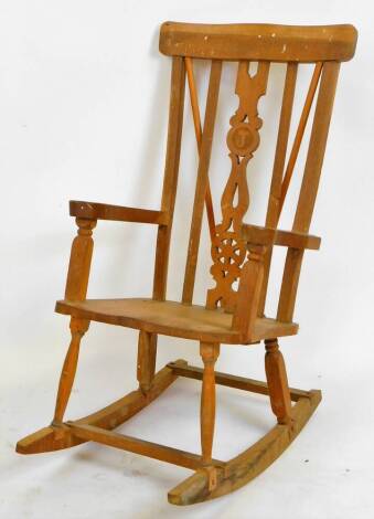 An early 20thC lightwood rocking chair, with comb top, pierced vertical splat, shaped arms and seat on turned legs, joined by a rocker base, 101cm H.