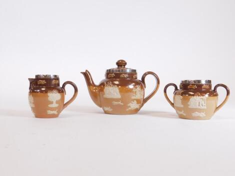 An early 20thC Royal Doulton stoneware three piece miniature tea service, with silver rims, comprising teapot, 10cm H, two handled sugar bowl and milk jug, Chester hallmarks, impressed marks beneath. (3)