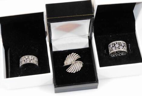 Three modern silver dress rings, comprising of two modern Pandora floral wedding type bands, one set with white stones, the other white and purple, in Pandora boxes and another Pandora fan type brooch set with white stones. (3)