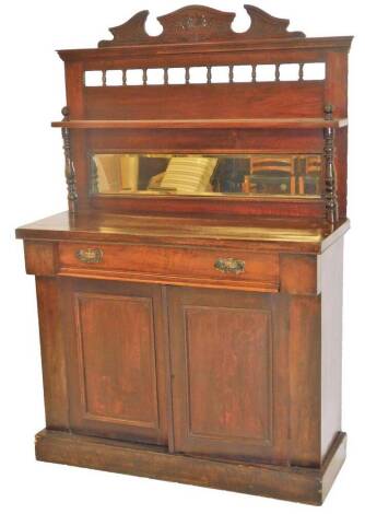 A late Victorian mahogany chiffonier, of small proportion, the carved top raised above an arrangement of urn spindles with a rectangular bevelled mirror flanked by further turned columns holding a shelf, above a frieze drawer and double cupboard beneath, 