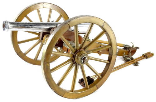 A miniature artillery type cannon, with chrome plated barrel, hardwood carriage and metal trunnion and cap, spoked wheels and hinged storage boxes. Sold with two separate ramrods, the barrell 38cm long, 72cm long overall.