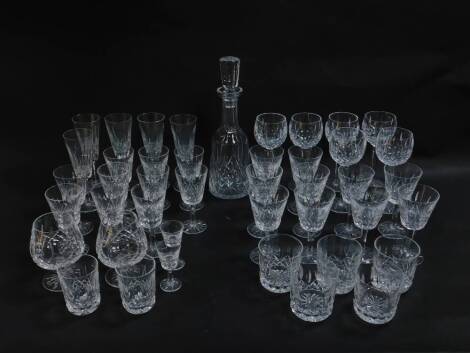 A Waterford Crystal part suite of cut glass tableware decorated in the Lismore pattern, comprising decanter and stopper, pair of brandy balloons, six hock glasses, five champagne flutes, four red wine glasses, six white wine glasses, ten further stem glas