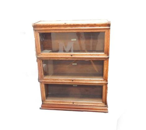 A Globe Wernicke oak bookcase, of triple section form, with glazed up and over doors, bears label, 86cm W x 30 1/2 cm D x 105cm H.