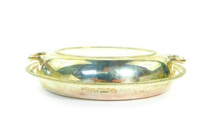 A George V silver twin handled entree dish and cover with gadrooned rims, Walker and Hall, Sheffield 1934, 31.21oz.