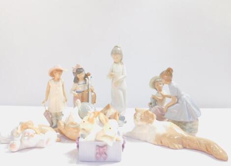 A group of Nao porcelain figures, including two girls with a doll, girl cello player, two puppies, cat, and a box of rabbits. (8)