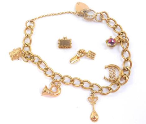 A 9ct gold charm bracelet, with five charms as fitted, on a heart shaped padlock clasp with safety chain and two further charms unfitted, 20.5g.