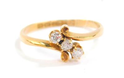 An 18ct gold and diamond three stone ring, in a cross over setting, approx 0.2cts, size R, 3.2g.