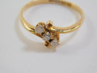 An 18ct gold and diamond three stone ring, in a cross over setting, approx 0.2cts, size R, 3.2g. - 3