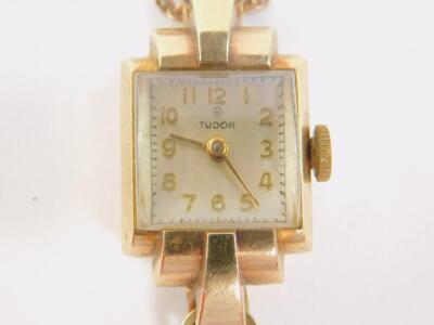 A Tudor lady's 9ct gold cased wristwatch, rectangular silvered dial bearing Arabic numerals, Swiss 17 jewel movement, in a Dennison plain rectangular case, on a 9ct gold bracelet, with safety chain as fitted, 15.5g. - 2