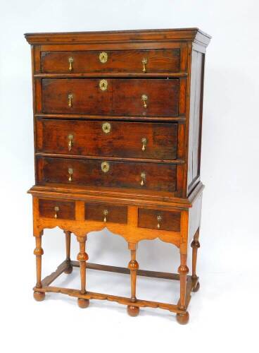 A mid 18thC oak chest on stand, the outswept pediment over four graduated drawers, the stand with three further drawers and a shaped apron, over turned columns united by a boxed stretcher, raised on bun feet, 98.5cm W, 55cm D, 165cm H.