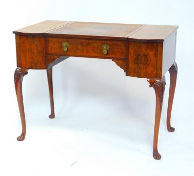 An early 20thC walnut breakfront desk, with a central square tooled leather writing surface above a single frieze drawer, flanked by two hinged bowfronted side sections, opening to reveal fitted interiors, raised on a leaf carved cabriole legs and fluted