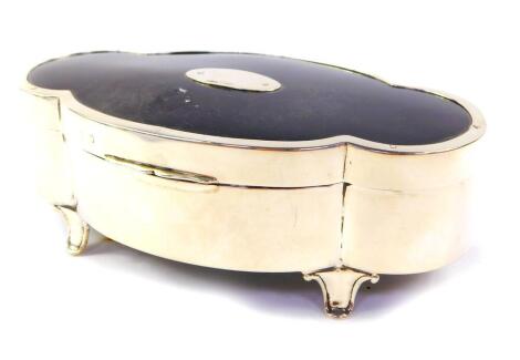 A George V silver and tortoiseshell jewellery casket, of lobed oblong form, the hinged lid set with an oval plaque, raised on four scroll feet, Mappin & Webb, Birmingham 1912, 16.5cm W, 9cm D.