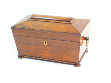 A Regency rosewood tea caddy of sarcophagus form, with ring handles, the hinged lid opening to reveal three recesses, raised on bun feet, 37cm w x 60 1/2 cm d x 21cm h