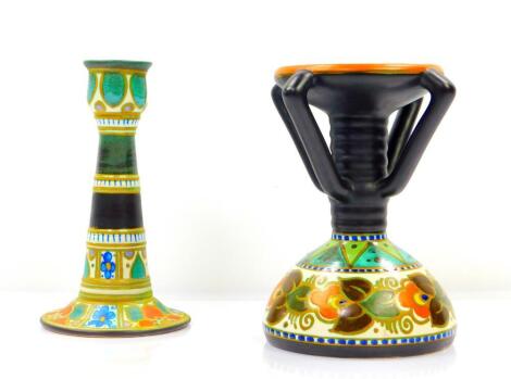 A Gouda Pottery candlestick, decorated in the Danier pattern, of four handled form, raised on a fluted stem and conical base, No 957/2674, painted marks, 21cm H, and a further pottery candlestick of outswept footed form, painted with flowers, Nos 1575 and