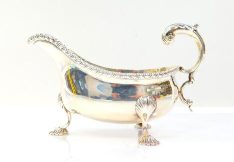 A Victorian silver sauce boat, with a gadrooned rim, double scroll handle, raised on three fluted hoof feet, Goldsmiths and Silversmiths Company, London 1900, 7.75oz.