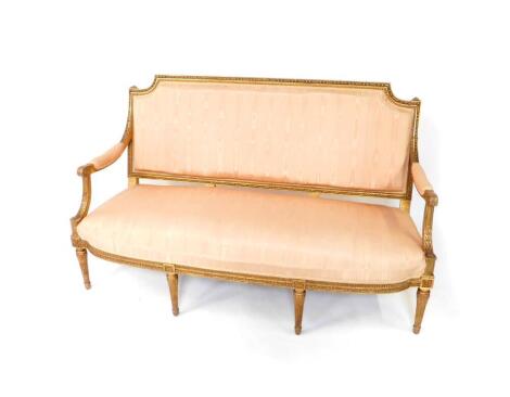 An early 19thC French style giltwood sofa, upholstered in over stuffed pink moire silk, with acanthus scroll open arms and raised on fluted tapering legs, 158cm W.