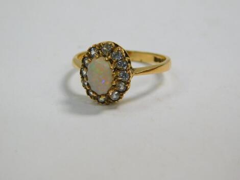 An 18ct gold and opal ring, set in a surround of clear brilliant cut stones, possibly white sapphires, size N, 2.4g.