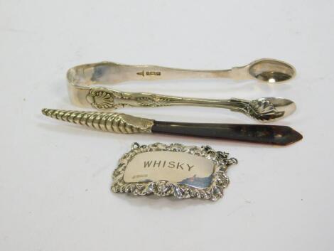 A pair of Edward VII King's pattern sugar tongs, Sheffield 1903, 1.43oz, Whiskey decanter label, Sheffield 1962, 0.46oz, and a Victorian silver and tortoiseshell letter opener, with spiral fluted handle, Birmingham 1892. (3)