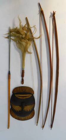 A tribal mask, 51cm H, 30cm W., fly swat, three bows and a spear, (6)