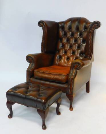 A Georgian style brown tan leather wing armchair, with button back and loose seat, raised on cabriole legs, 109cm high, 81cm wide, together with a matching foot stool, 48cm wide (2).