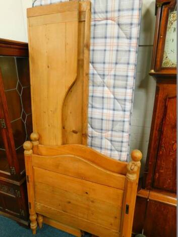 A pine single bed, with pine head board, foot board and two side boards with slats and a single mattress.