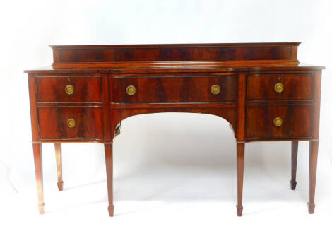 An Edwardian mahogany and crossbanded breakfront sideboard, with a panelled back, central fitted bow fronted drawer, flanked by a cupboard and a lead lined wine cooler, raised on tapering square legs and spade feet, 108cm high, 183cm wide, 63cm deep.