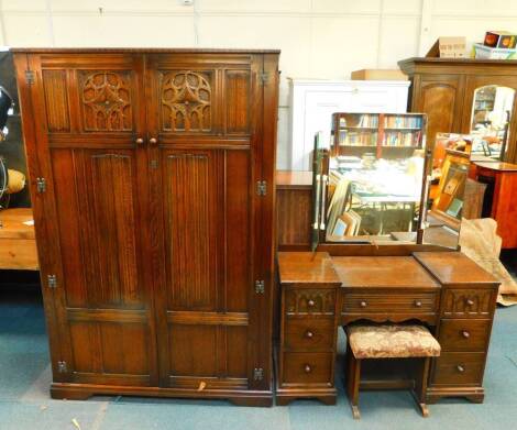 A Tudor style oak double wardrobe, with linenfold and Gothic arch tracery panelled doors, opening to reveal a shelf above hanging space, raised on bracket feet, 185.5cm H, 123cm W, 52cm D., together with a dressing table with a tryptic glass mirror above 