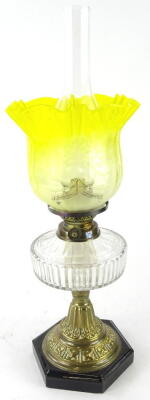 An early 20thC oil lamp, with clear funnel marked fire proof, with bear stamp, yellow clear and etched glass shade, brass shoulder, clear reservoir, and acanthus leaf stem, terminating in an octagonal base, 59cm high.