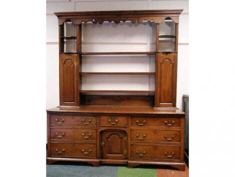 A George III oak dresser with moulded and shaped canopy top with open plate