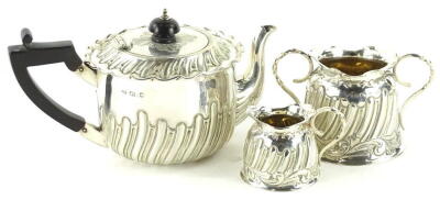 A Victorian silver three piece tea service, comprising teapot, the shaped lid with gadrooned border and ebonised knop, the cylindrical body partially gadrooned with shaped spout and ebonised handle, on a compressed circular foot, Sheffield 1892, 10cm high