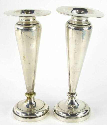 A pair of Edwardian silver specimen vases, each with compressed rims, shouldered tapering stems and circular feet, Birmingham 1910, 19cm high, 16oz all in (2, weighted)