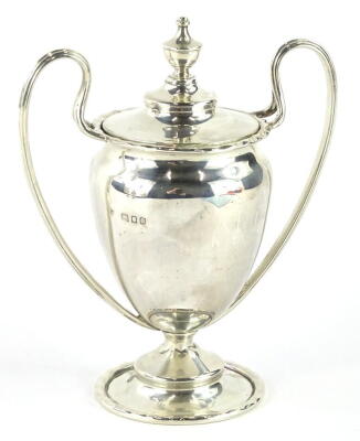 A George V silver trophy, with urn finial, compressed domed lid, flanked by strap handles, on a squat inverted stem and circular domed foot, London 1919, 14cm high, 4½oz.