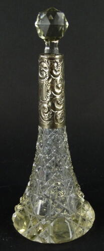 A late 19thC cut glass perfume bottle, with white metal repousse decorated collar, orb stopper and trumpet shaped body, decorated with a repeat hob nail cut geometric pattern, unmarked, 23cm high.