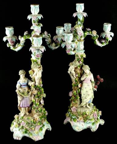 A pair of late 19thC Sitzendorf candelabra, each with four branches, decorated with flowers and leaves overall and with figural bases, factory mark in blue underneath, 56cm H.