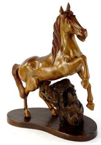 A 20thC heavily carved treen figure of a horse, with front leg raised, 40cm H, on a naturalistic base. (AF)