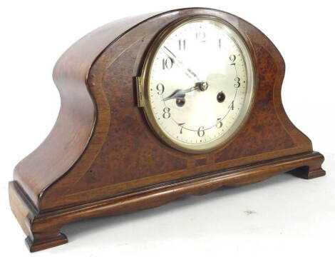 An early 20thC burr walnut and mahogany mantel clock, the shaped case with a wide crossbanding on bracket feet, with a 15cm diameter silvered Arabic dial, revealing an eight day movement, 23cm high, 42cm wide, 11cm deep.