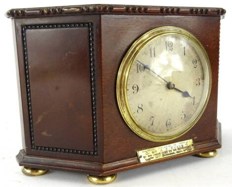 An early 20thC mahogany cased mantel clock, in shaped case, with upper beading on compressed orb feet, fronted by a plaque reading A E Evans, 31st December 1926, with 8cm diameter Arabic dial, with key, 15cm high, 24cm wide, 7cm deep.