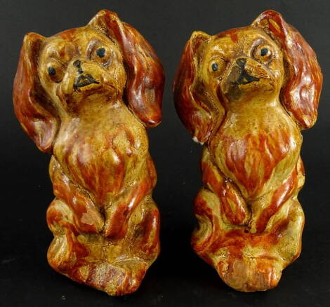 A pair of plaster figures of standing King Charles Spaniels, each in orange and yellow colourway, with black eyes, 18cm high.