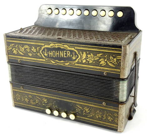 An early 20thC Hohner Marca accordion, with meshwork grill front, four upper and ten lower buttons, in floral decoration on a black ground, with a black leather strap, 15cm high, 28cm wide, 24cm deep.